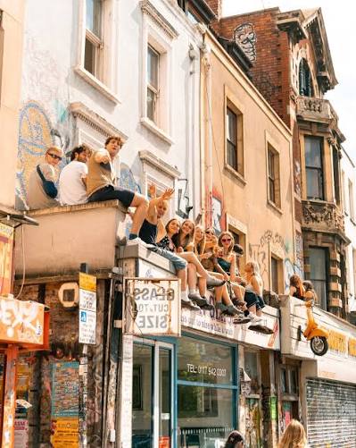 Friends sitting above street-art covered shopfronts in Stokes Croft, Bristol